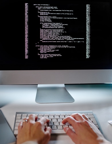 Hands of young female programmer typing on keyboard while sitting by workplace in front of computer screen and decoding data